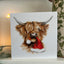 Highland cow with Christmas hat in its mouth