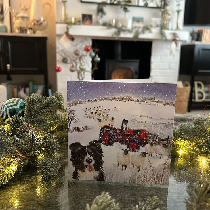 Sheep dog and tractor in snowy field Christmas card