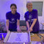Jenny at a bake sale in a purple tshirt with the Pancreatic Cancer UK logo in white