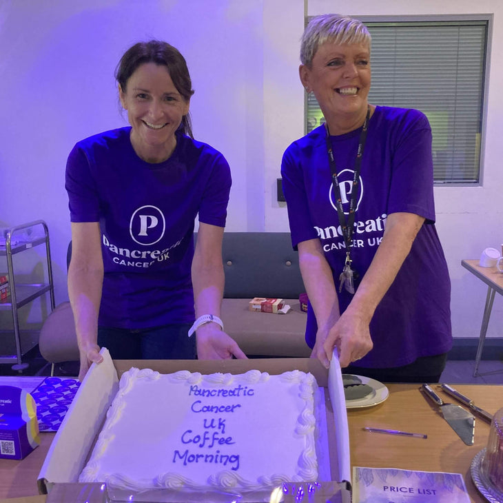 Jenny at a bake sale in a purple tshirt with the Pancreatic Cancer UK logo in white
