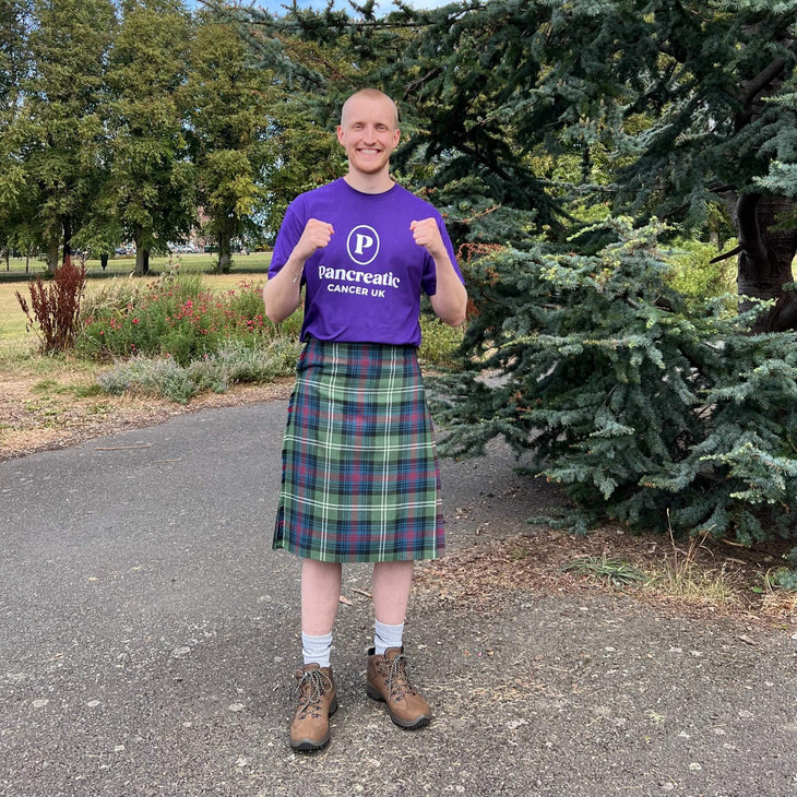 Tom, wearing a purple tshirt with the Pancreatic Cancer UK logo on it